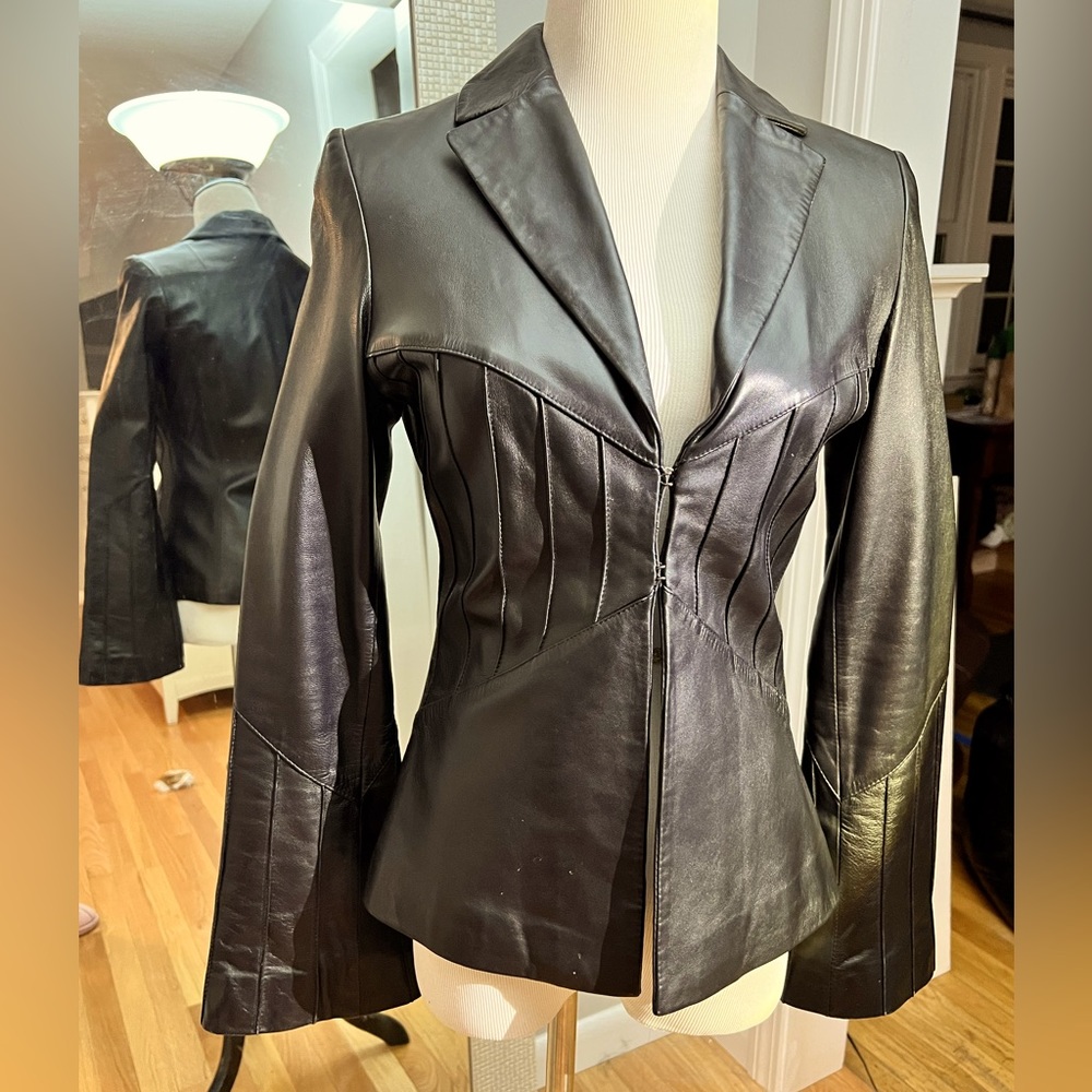 Black leather jacket with bell sleeves and 2 front hook closures. Excellent